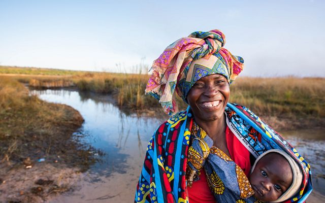 A woman and her child cross the Cuito River in Livambi Village, Angola, early in the morning.
