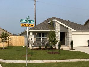 A street sign named "Butterfly Way" leading towards pollinator gardens in a housing addition.