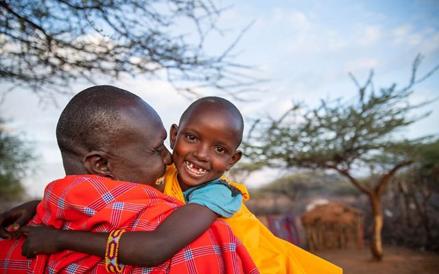 a man holding a child, smiling at the camera.