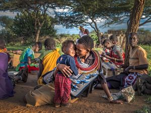 Ntipiyon Nonguta and son Bernard relax with their neighbors as they make beaded belts in Laikipia, northern Kenya. Their stunning designs are available worldwide.