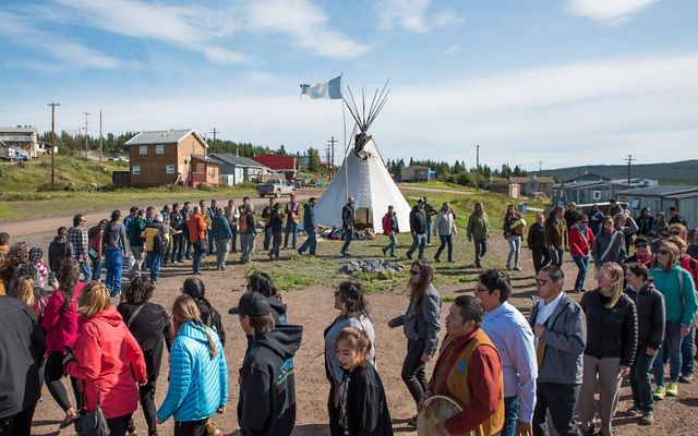 Men women and children of lutsel ke first nation dance in a circle near a tipi in a first nations native american community