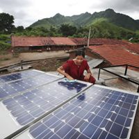 Photo of a woman in India working on a solar panel in her village.