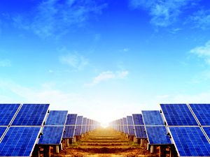 Looking between two large arrays of solar panels, blue sky above.