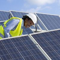 Electrical engineer woman checking solar photovoltaic panels on the roof of a solar farm. 