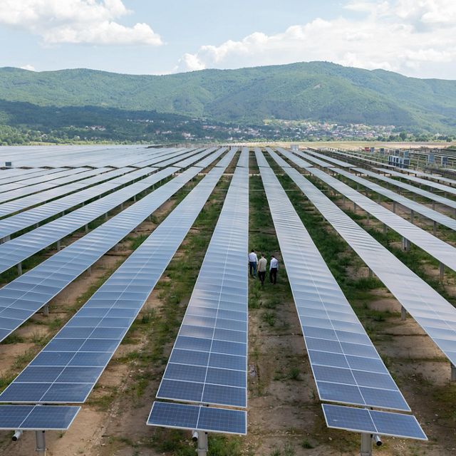 Aerial view of people walking among rows of solar panels.
