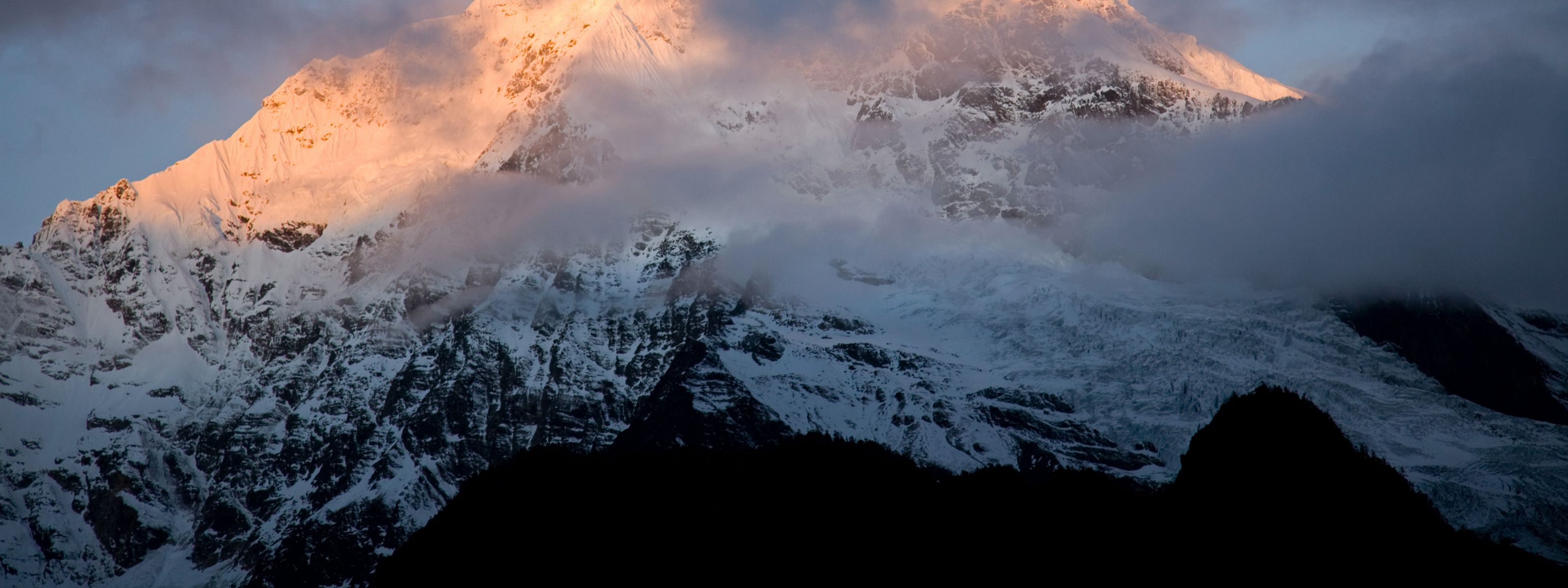 Fog stretches across a snow-covered mountain range.