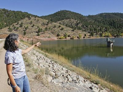 Laura McCarthy points to area adjoining Nichols Reservoir (second hillside from left) where management practices have reduced forest density to fire-safe levels.