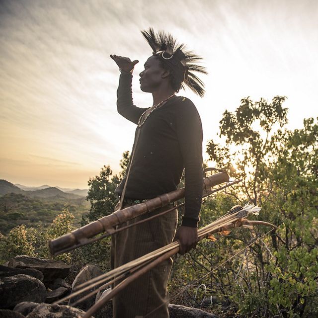 Backlit by a bright sun, a man wearing a traditional he