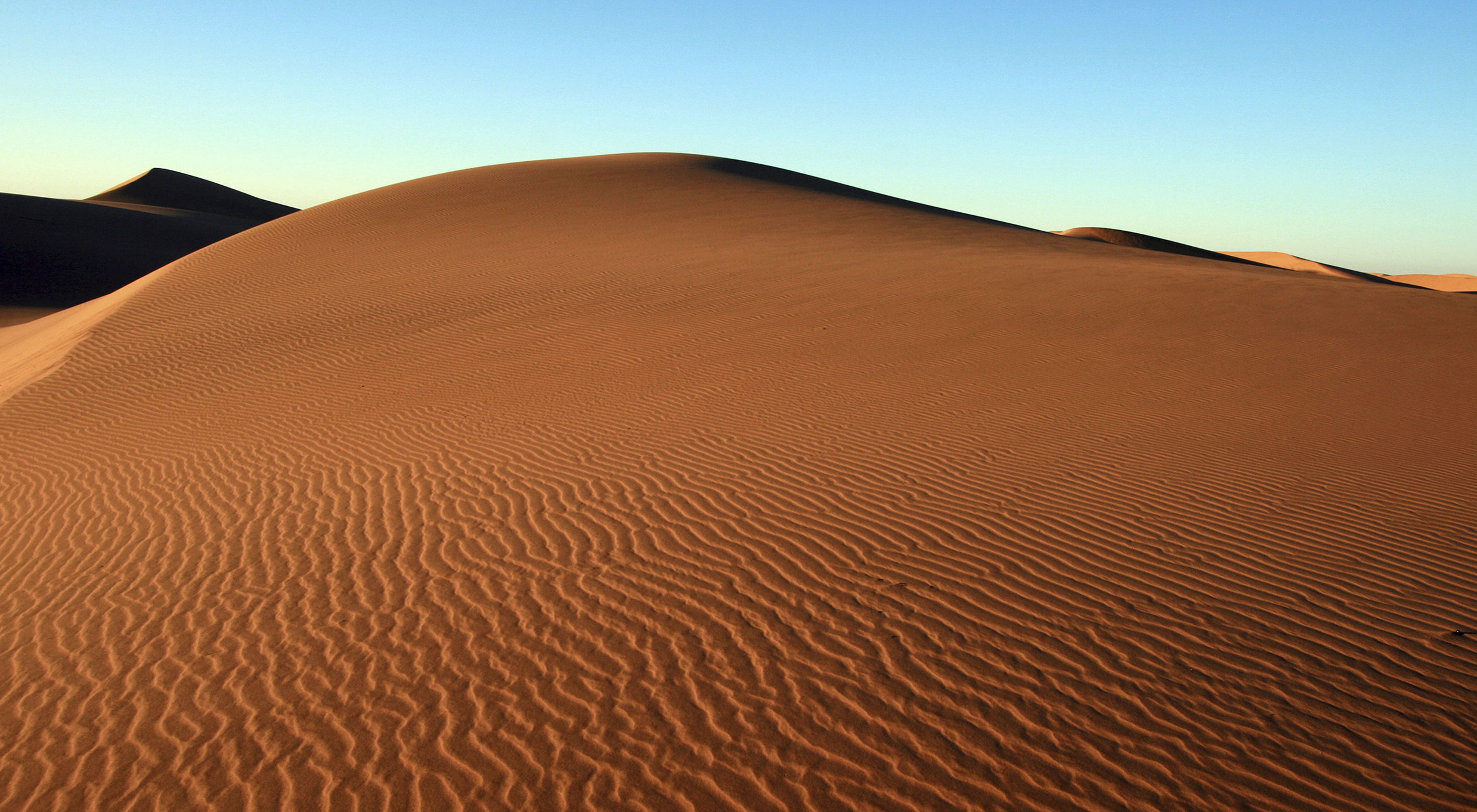 A massive reddish sand dune, with ripples showing trace