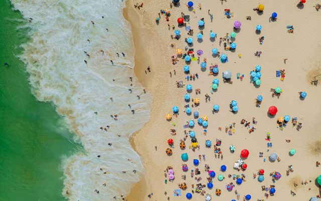 aerial view of beachgoers with colorful umbrellas on a beach on the ocean