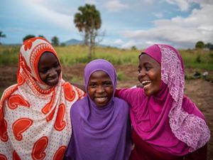 three girls standing together and smiling.