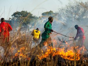 A fire training participant runs behind a fire line 