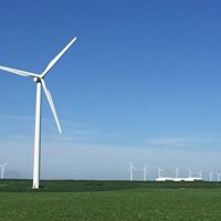 Photo of a wind turbine in a broad, flat Iowa field, with other turbines in background.